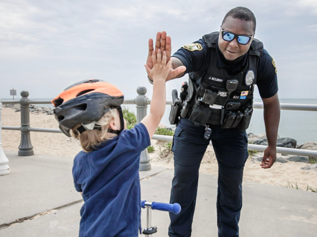 Male police officer giving high five to young child
