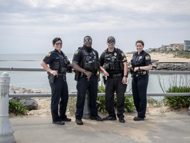 Group of four police officers posed for camera near water