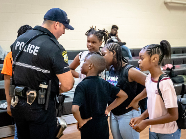 Police officer speaking with kids in gym during school event