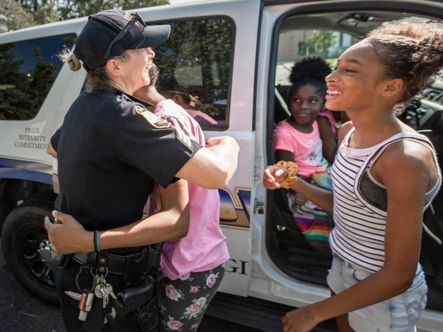 Female police officer getting a hug from a young girl during community event