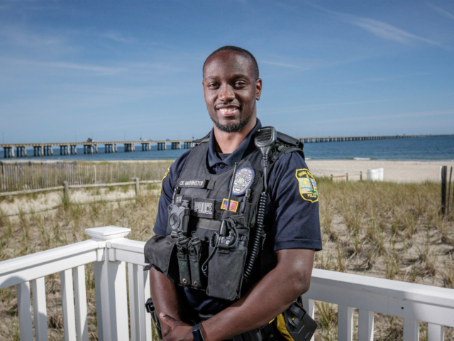 African American police officer smiling at camera on the beach Careers header
