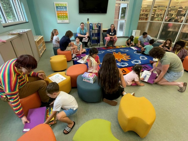 Group of children and adults in Library activity room with books