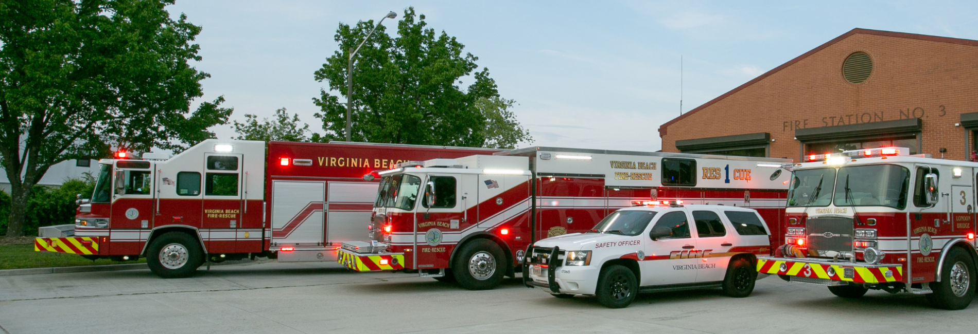 Fire trucks and vehciles with emergency lights on parked in front of fire station